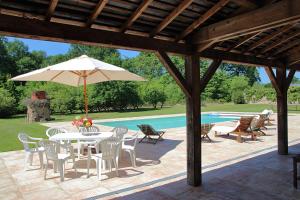eine Terrasse mit einem Tisch, einem Sonnenschirm und einem Pool in der Unterkunft Orangerie de la Touchardière in Durtal