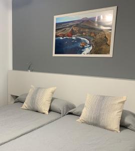- un lit avec 2 oreillers et une photo au-dessus dans l'établissement Relax Tiñosa Apartment, à Puerto del Carmen