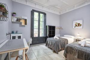 a white room with two beds and a table and a table at ELLA Guest House Barcelona in Barcelona