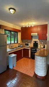a large kitchen with wooden cabinets and a refrigerator at Kwezi Cottage at The Great Rift Valley Lodge & Golf Resort Naivasha in Naivasha