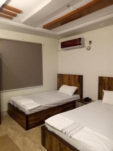 une chambre avec deux lits et un écran de projection dans l'établissement Pearl Cottage Airport, à Karachi