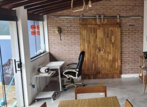 um escritório com uma cadeira, uma secretária e uma parede de tijolos em CASA AZUL São Pedro em São Pedro