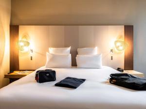 two bags sitting on top of a white bed at Mercure Grenoble Meylan in Meylan