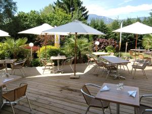 una terraza de madera con mesas, sillas y sombrillas en Mercure Grenoble Meylan en Meylan