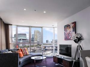 a living room with a couch and a large window at The Sebel Melbourne Docklands Hotel in Melbourne