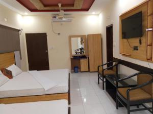 Cette chambre comprend un lit, une table et une télévision. dans l'établissement Pearl Cottage Airport, à Karachi