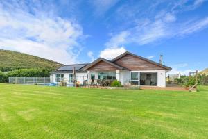 une maison avec une grande pelouse devant elle dans l'établissement Green View - Parua Bay Holiday Home, à Parua Bay