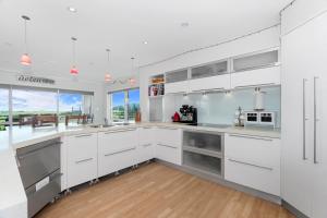 a kitchen with white cabinets and a large window at Green View - Parua Bay Holiday Home in Parua Bay