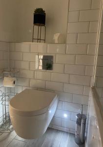a white tiled bathroom with a toilet and a plant at Sofias Flat in Bournemouth