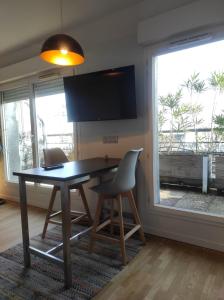 a dining room with a table and chairs and a large window at Studio avec terrasse proche des transports. in Issy-les-Moulineaux