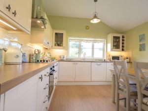a kitchen with white cabinets and a counter top at Pass the Keys Porth Vaynor Farmhouse and Gardens in Usk