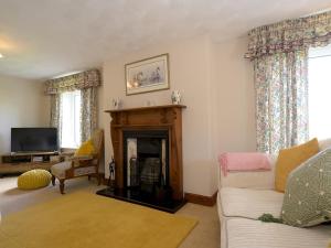 a living room with a fireplace and a tv at Pass the Keys Porth Vaynor Farmhouse and Gardens in Usk