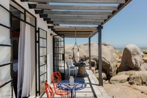 a patio with a table and chairs and rocks at Into the Mystic in Paternoster