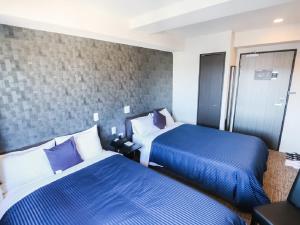 2 camas en una habitación de hotel con sábanas azules en HOTEL LiVEMAX Hachioji Ekimae, en Hachioji