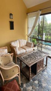 Kwezi Cottage at The Great Rift Valley Lodge & Golf Resort Naivasha في نيفاشا: غرفة معيشة مع أريكة وطاولة قهوة