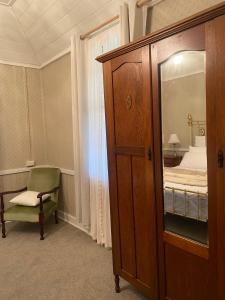 a bedroom with a cabinet and a chair and a bed at Ulva Cottage - Historical BnB in Penola