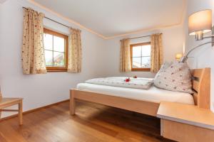 a bedroom with a bed and two windows at Ferienhaus Mittersill am Biohof Widholz in Mittersill