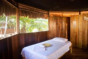 Cama en habitación de madera con ventana en Eywa Lodge Amazonas - All inclusive en Yucuruche