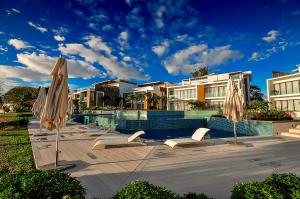 a swimming pool with umbrellas and lounge chairs at Cap Ouest Luxury Beachfront in Flic-en-Flac