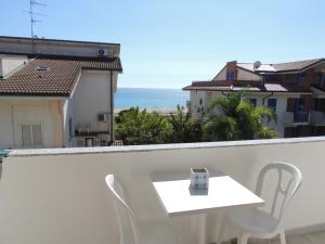 una mesa blanca y sillas en un balcón con vistas al océano en B&B a due passi dal mare en Caulonia Marina