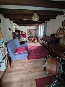 ein Wohnzimmer mit einem blauen Sofa und einem Klavier in der Unterkunft Magnifique Moulin au bord d'une riviere, calme absolu, piano in Doyet