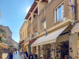 a group of people walking down a street with shops at Hadrians Den in Heart of Plaka by JJ Hospitality in Athens