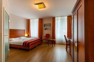 a bedroom with a bed and a table and a chair at Hotel Am Mühlenteich in Schwelm