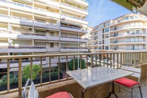 einen Balkon mit einem Tisch und Stühlen sowie ein Gebäude in der Unterkunft Cozy studio in the heart of Cannes - Near sea in Cannes