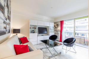ein Wohnzimmer mit einem weißen Sofa und roten Kissen in der Unterkunft Cozy studio in the heart of Cannes - Near sea in Cannes