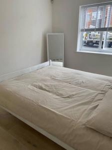 uma cama grande num quarto com uma janela em Spacious and Cosy 2 Bedroom Flat in Bermondsey em Londres