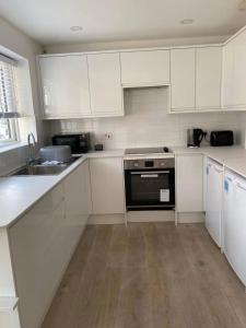 a kitchen with white cabinets and a sink and a stove at Spacious and Cosy 2 Bedroom Flat in Bermondsey in London