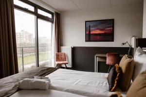a bedroom with a bed and a large window at Hotel Torpedoloods in Hoek van Holland