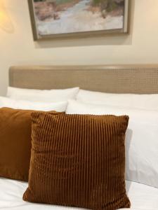 a brown pillow sitting on a bed with white pillows at St Duthus Villa Guesthouse in Tain