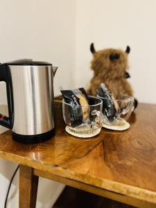 a teddy bear sitting on a table with a coffee pot at St Duthus Villa Guesthouse in Tain