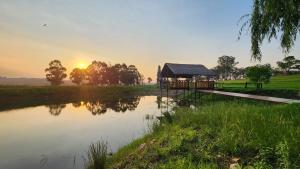 a building next to a lake with the sunset in the background at Echo Valley Guest Farm in Breyten