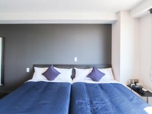 2 bedden met blauwe en witte kussens in een slaapkamer bij HOTEL LiVEMAX Takadanobaba Ekimae in Tokyo