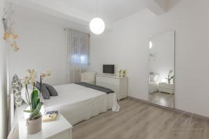 Habitación blanca con cama y espejo en Un'Oasi di Pace, en Ferrara