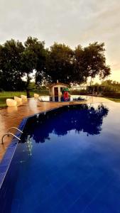 a large blue swimming pool with a house in the background at Pousada Marajoara- Hotel Fazenda-Turismo de Aventura in Soure