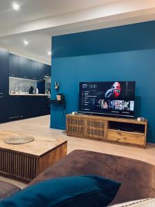 uma sala de estar com uma grande televisão de ecrã plano numa parede azul em NARCISSE Balnéo, Sauna, Hammam em Reims