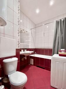 a red and white bathroom with a toilet and a sink at Чарівна, простора квартира в 2хв від МВЦ, Лівобережна in Kyiv