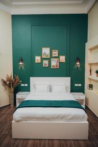 een slaapkamer met een groot bed met een groene muur bij Hathor House in Caïro