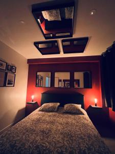 um quarto com uma cama com paredes vermelhas e espelhos em NARCISSE Balnéo, Sauna, Hammam em Reims
