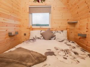a bed in a log cabin with a window at Cherry in Ulverston