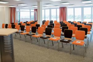 an empty room with orange and black chairs at Bernsteinsee Hotel in Sassenburg