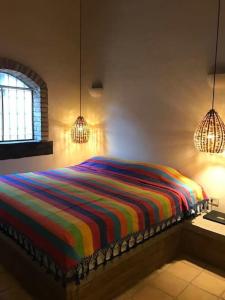 um quarto com uma cama com um cobertor listrado colorido em Casa Rustica en la Reserva Tehuacán-Cuicatlán 