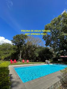 a swimming pool with two red chairs and a swimming pool at La Casa de los Patos in Valle de Anton