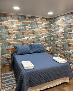 um quarto com uma cama azul e uma parede de tijolos em Hotel Restaurante Aconcagua em La Ligua