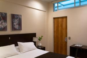 1 dormitorio con 1 cama y puerta de madera en Hotel Plaza Cienfuegos, en Talca