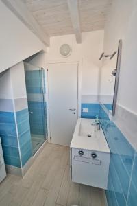 uma casa de banho azul e branca com um lavatório e um chuveiro em Affittimoderni Isola Rossa Borgo - IRGI11 em Isola Rossa