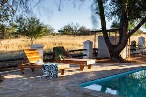 a couple of chairs sitting next to a swimming pool at Naos Farm Stay 